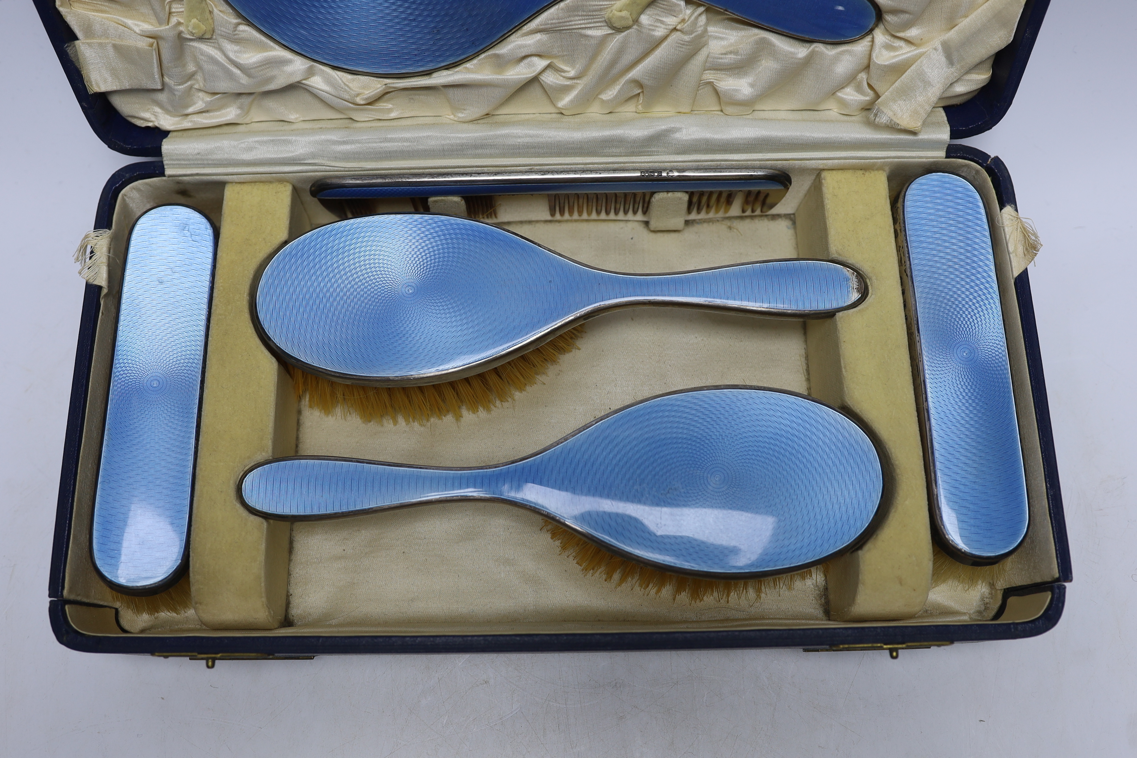 A cased George V silver and blue guilloche enamel mounted six piece mirror and brush set, Charles Henry Dumenil, London, 1932.